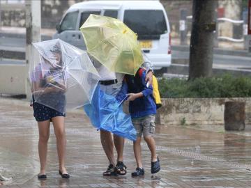 Varios viandantes luchan contra los fuertes vientos y la lluvia