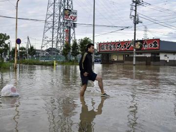 Un joven se abre paso entre las calles abnegadas por el agua en Japón.