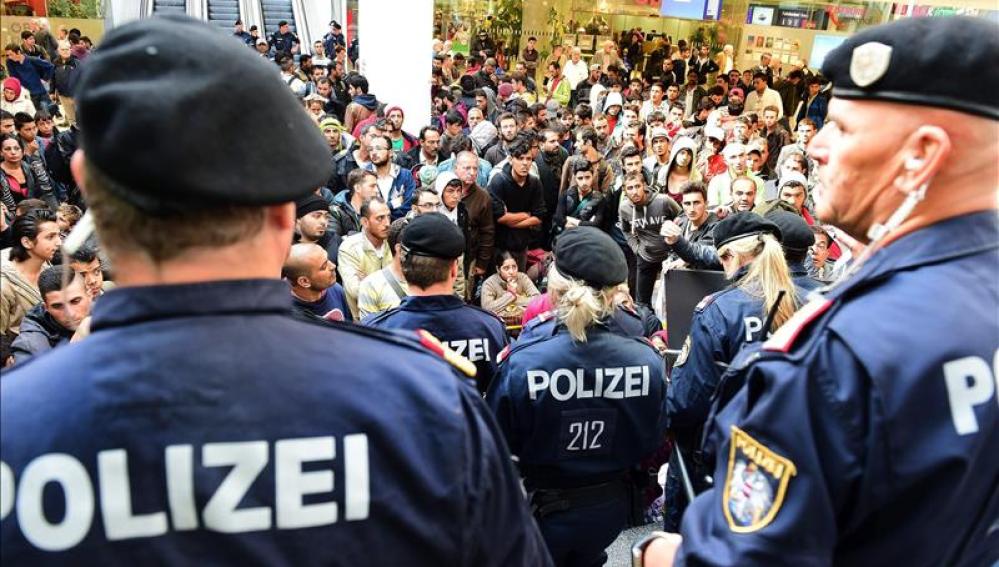 Policías frente a los cientos de refugiados que esperan la llegada de más trenes con dirección a Alemania.