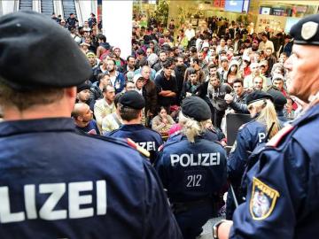 Policías frente a los cientos de refugiados que esperan la llegada de más trenes con dirección a Alemania.