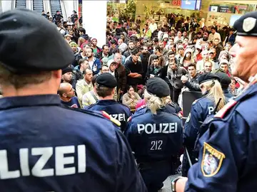 Policías frente a los cientos de refugiados que esperan la llegada de más trenes con dirección a Alemania. Policías frente a los cientos de refugiados que esperan la llegada de más trenes con dirección a Alemania.