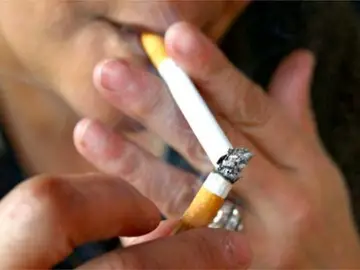 Una persona encendiéndose un cigarro Una persona encendiéndose un cigarro