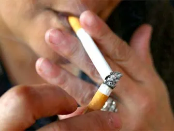 Una persona encendiéndose un cigarro Una persona encendiéndose un cigarro