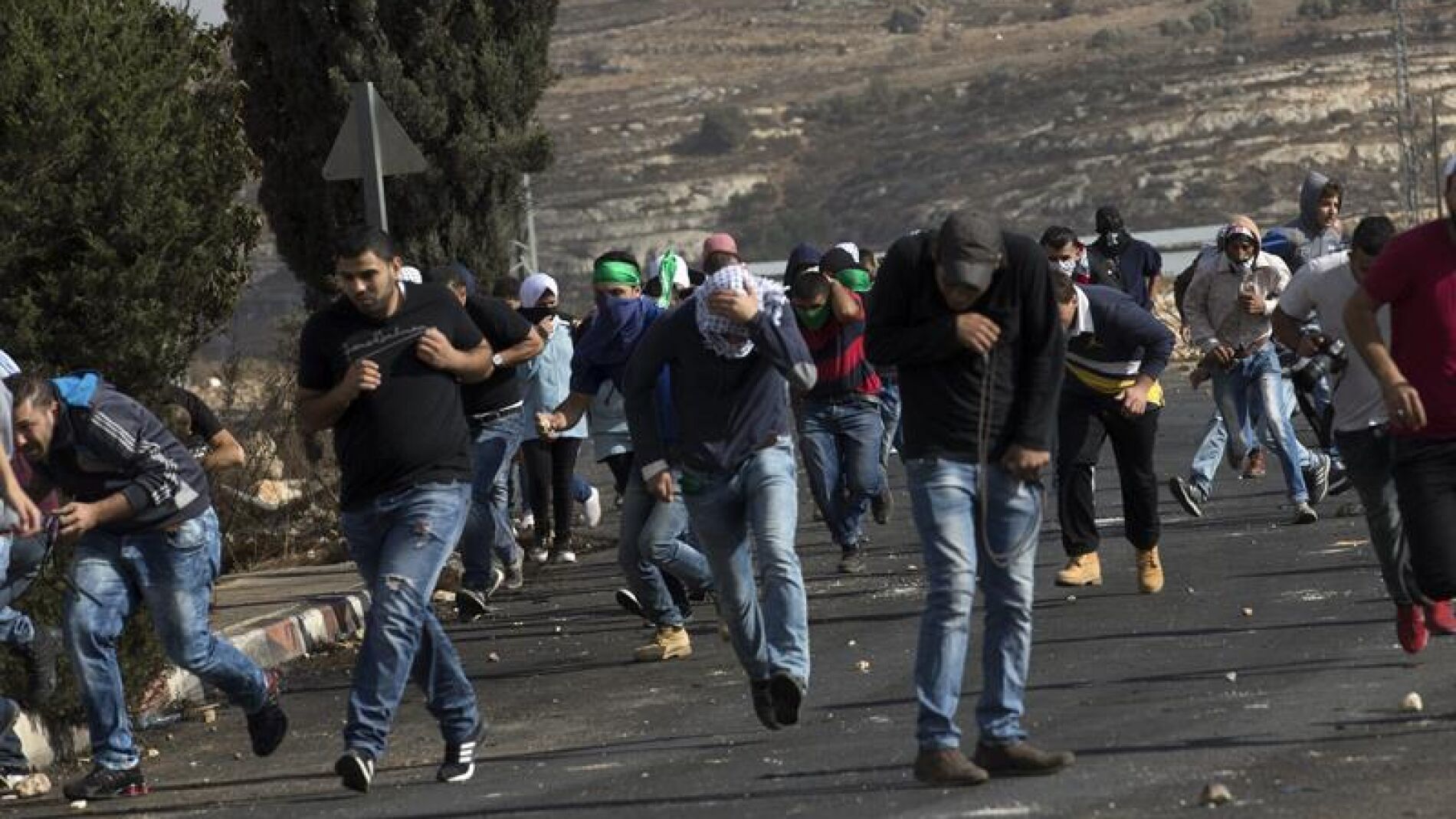 Palestinos corren para ponerse a cubierto durante un enfrentamiento con el Ej&eacute;rcito israel&iacute; en Ramala