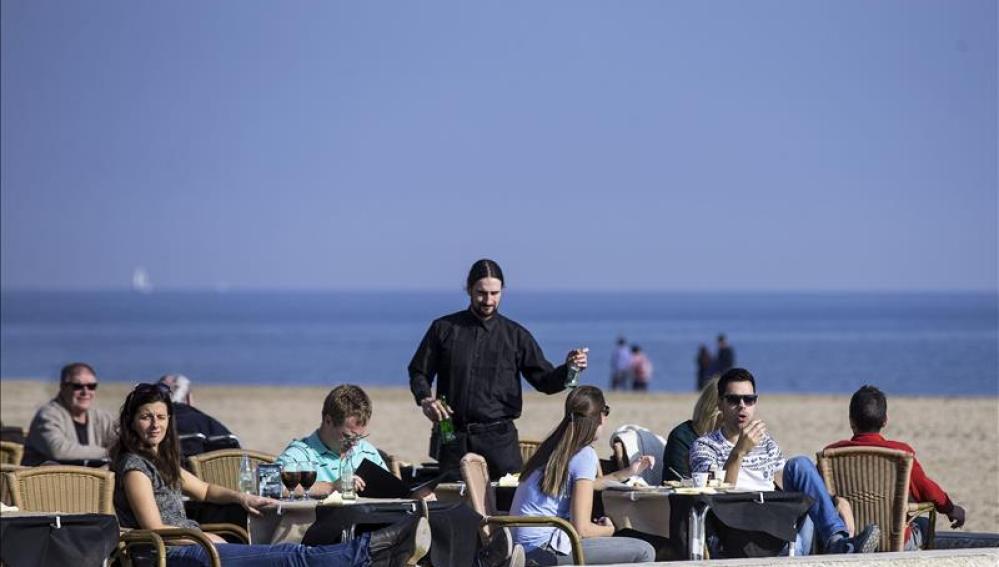 Varias personas disfrutan de las temperaturas suaves tomando un aperitivo en una terraza