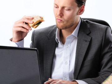 Un hombre comiendo un bocadillo en el trabajo
