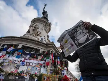 Un hombre lee la revista Charlie Hebdo frente al homenaje a las víctimas Un hombre lee la revista Charlie Hebdo frente al homenaje a las víctimas