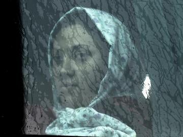 Una mujer inmigrante mira a través de la ventana