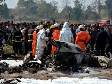 Bomberos y miembros de los servicios de rescate inspeccionan los restos de un avión militar siniestrado