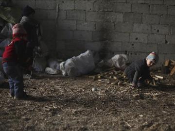 Un grupo de niños sirios mientras recogen leña en un almacén de Damasco