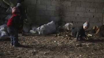 Un grupo de niños sirios mientras recogen leña en un almacén de Damasco