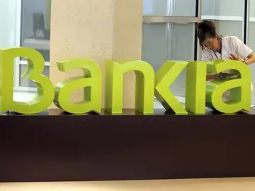 Una operaria limpia el logo de Bankia Una operaria limpia el logo de Bankia