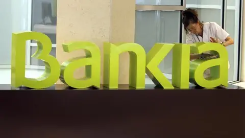 Una operaria limpia el logo de Bankia Una operaria limpia el logo de Bankia