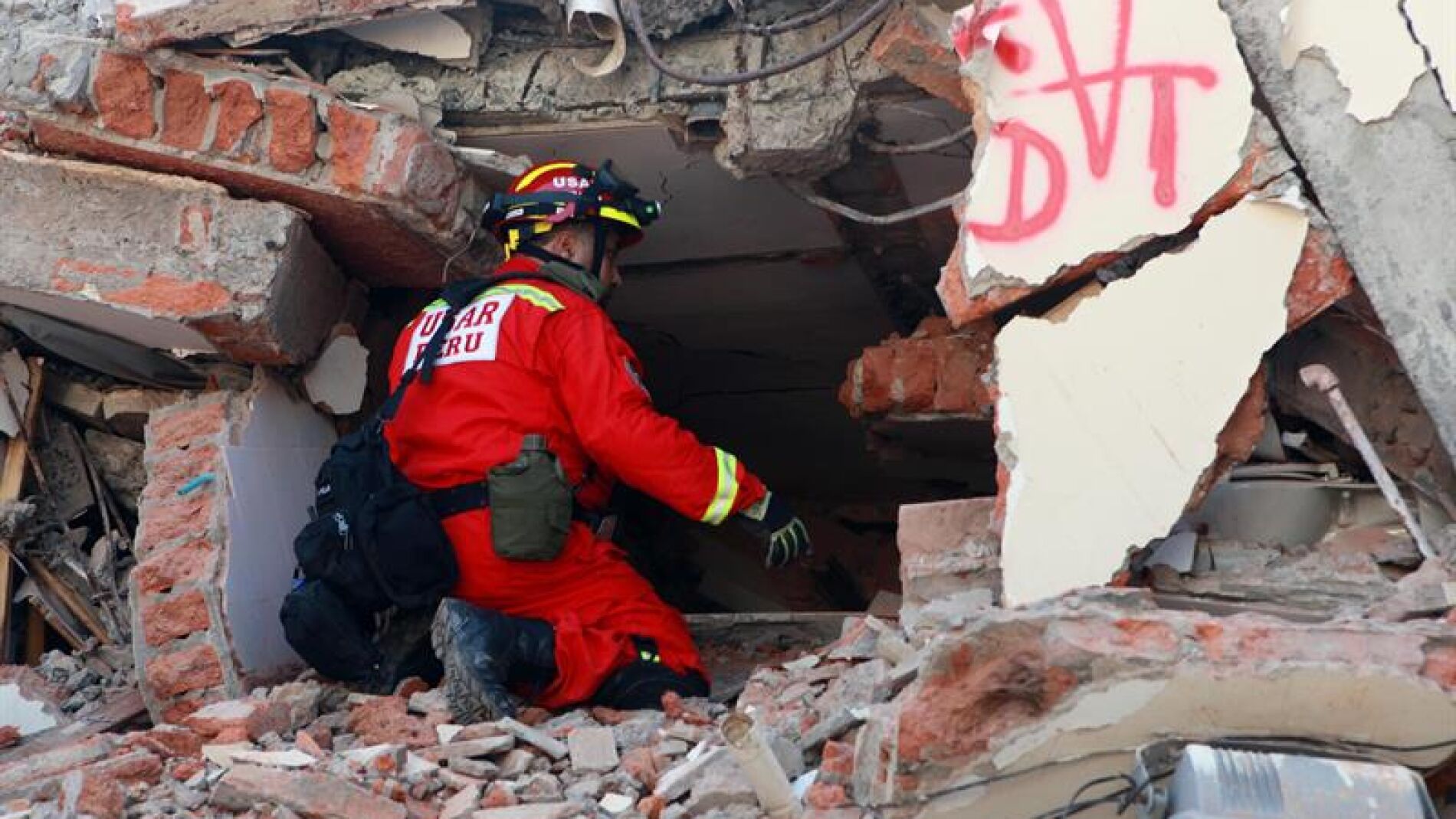 Un bombero busca v&iacute;ctimas entre los escombros