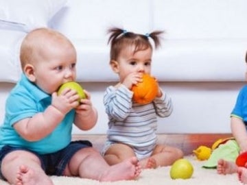 Varios bebés comiendo fruta