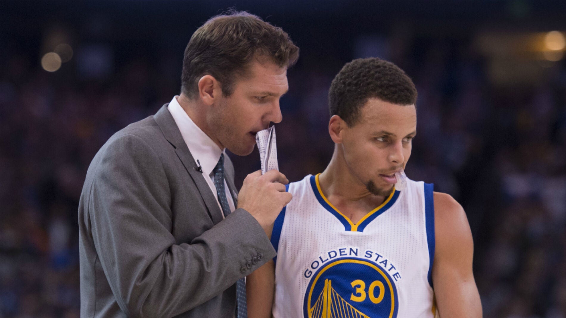 Luke Walton dialoga con Stephen Curry durante un partido
