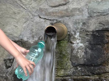 Imagen de una persona llenando una botella de agua