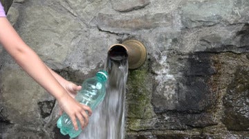 Imagen de una persona llenando una botella de agua