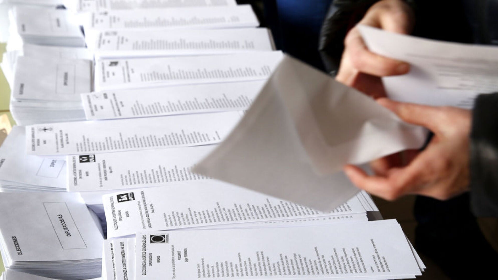 Una persona introduce una papeleta electoral en un sobre.