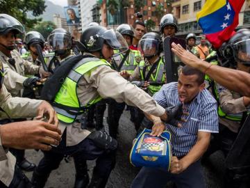  Miembros de la Policía Nacional Bolivariana forcejean con un manifestante 