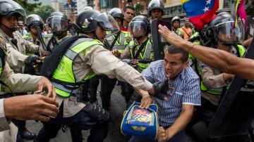  Miembros de la Policía Nacional Bolivariana forcejean con un manifestante 