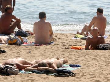 Varias personas practican nudismo en una playa