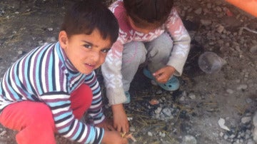 Dos niños recogen comida del suelo en Idomeni