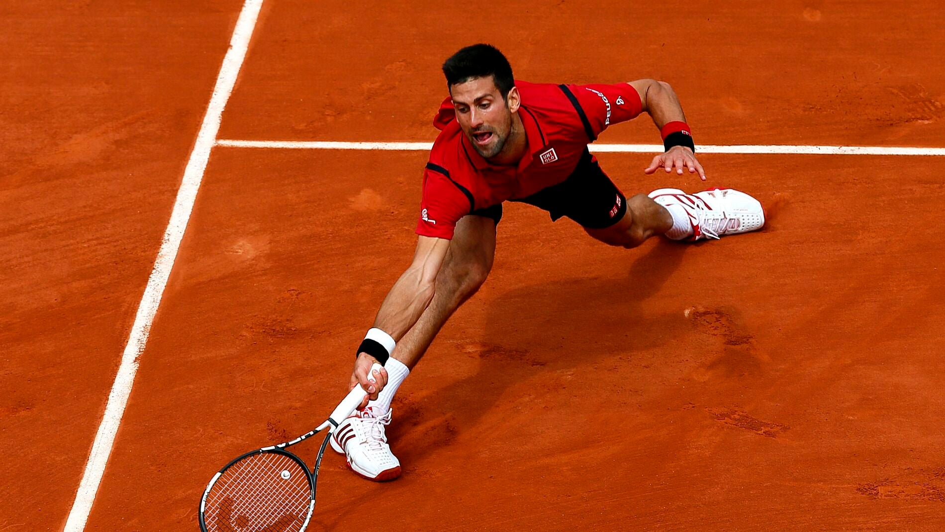 Novak Djokovic estir&aacute;ndose para alcanzar la pelota en Roland Garros