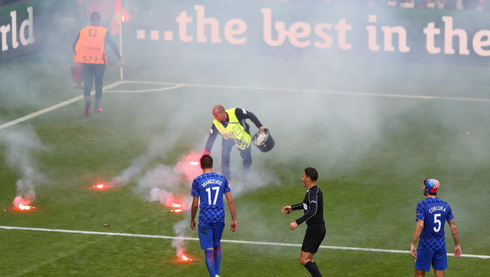 Un empleado de la UEFA retira bengalas del césped