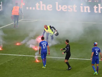 Un empleado de la UEFA retira bengalas del césped Un empleado de la UEFA retira bengalas del césped