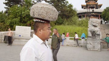 Cong Yan caminando con una piedra en la cabeza