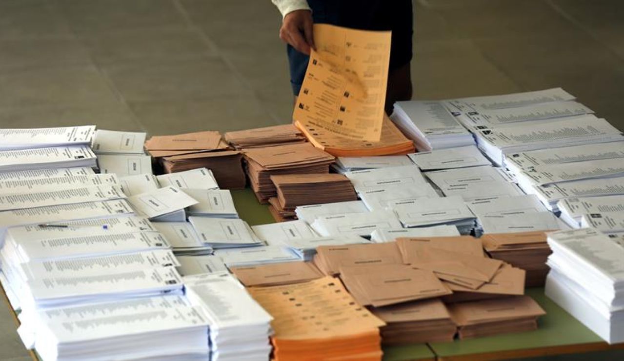 Un votante selecciona las papeletas antes de votar Un votante selecciona las papeletas antes de votar