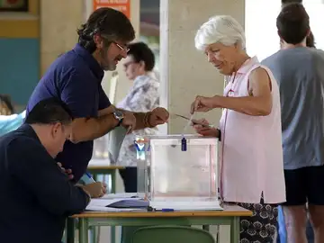 Una mujer deposita su voto en una urna de un colegio electoral Una mujer deposita su voto en una urna de un colegio electoral