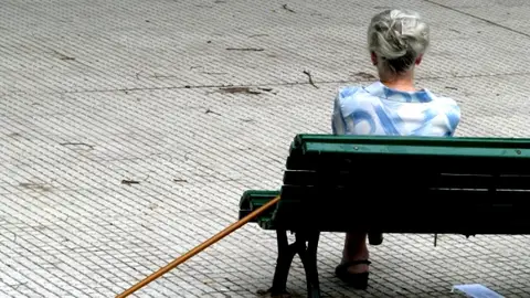 Una mujer mayor sentada en un banco Una mujer mayor sentada en un banco