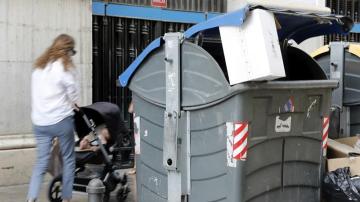 Una madre con su bebé pasa junto a un contenedor