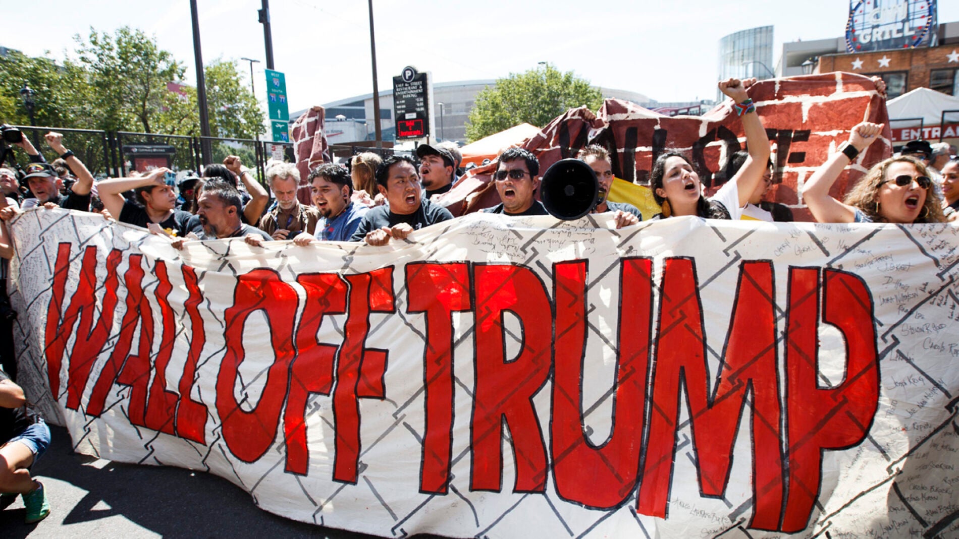 Manifestantes con una pancarta que pone: "Amurallar a Trump"