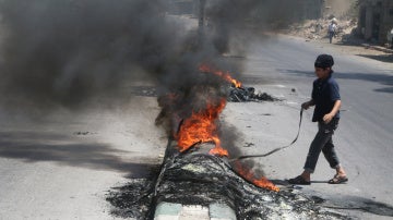 Un niño junto a una pila de neumáticos ardiendo en Alepo