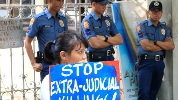 Una joven sujeta una pancarta contra los asesinatos en Manila