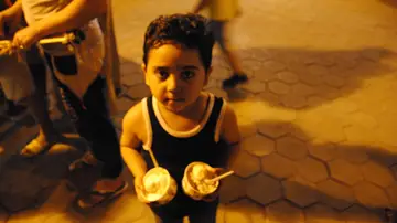Niño desfavorecido sostiene dos helados Niño desfavorecido sostiene dos helados