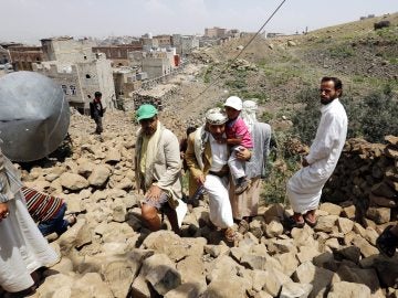 Yemeníes inspeccionan una casa destruida por aviones en Saná, Yemen