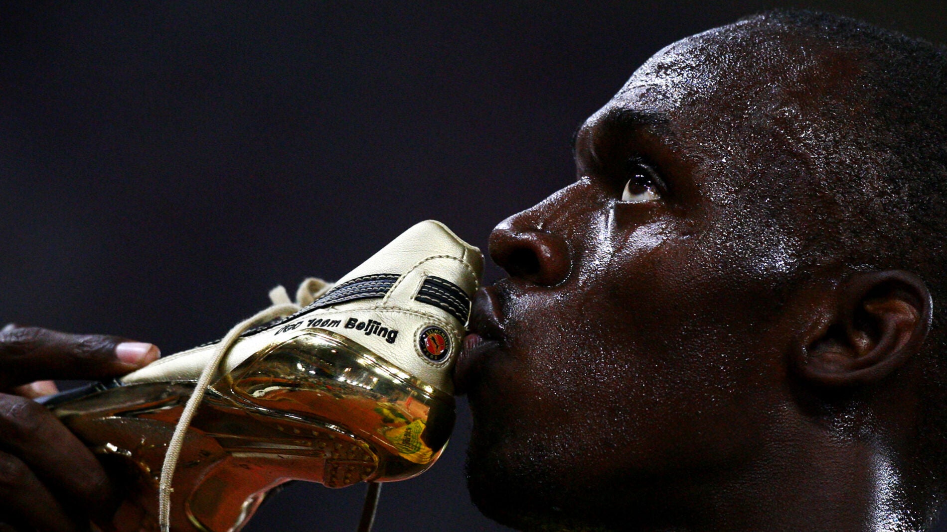 Usain Bolt besa una de sus zapatillas tras la carrera de los 100 metros de los Juegos de Pek&iacute;n