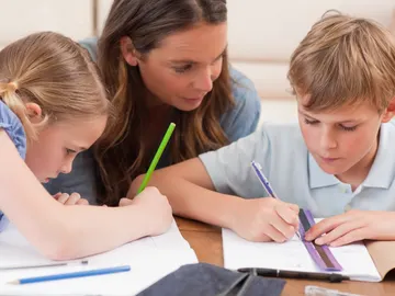 Una madre ayudando a sus hijos con los deberes Una madre ayudando a sus hijos con los deberes