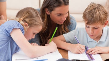 Una madre ayudando a sus hijos con los deberes