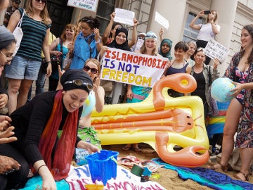 Los manifestantes de diferentes sociedades realizar una manifestación denominada ' Wear What You Want ' con temas como un estilo de fiesta en la playa , frente a la embajada francesa en Londres