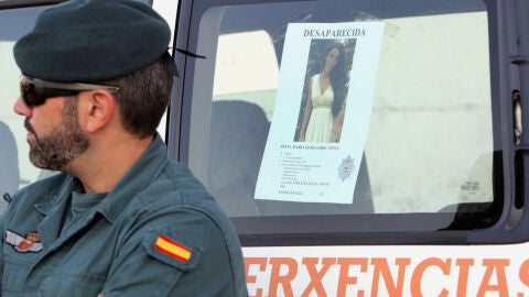 Un efectivo de la Guardia Civil junto al cartel de la joven Diana Quer