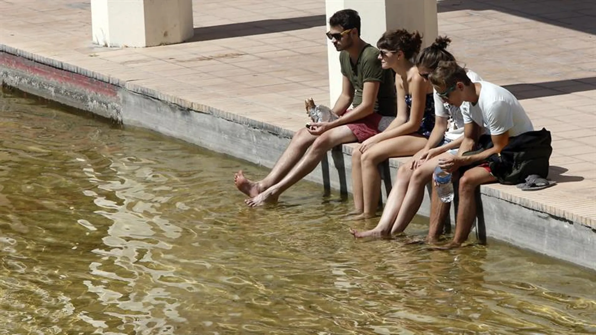 Un grupo de jóvenes se refresca los pies Un grupo de jóvenes se refresca los pies