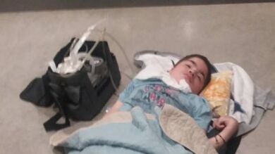 Un niño enfermo terminal espera en un aeropuerto tirado en el suelo porque no le ofrecen una silla, mantas ni agua