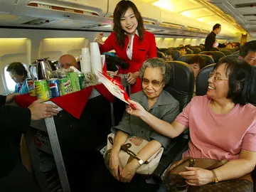 Una auxiliar de vuelo atendiendo a una pasajera Una auxiliar de vuelo atendiendo a una pasajera