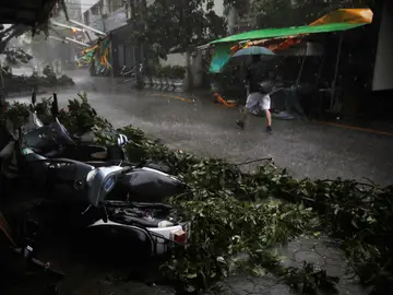 Un hombre camina por la calle frente a unas motocicletas desplazadas por el tifón Megi en Hualien, Taiwan Un hombre camina por la calle frente a unas motocicletas desplazadas por el tifón Megi en Hualien, Taiwan