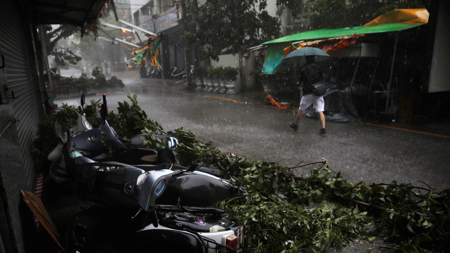 Un hombre camina por la calle frente a unas motocicletas desplazadas por el tif&oacute;n Megi en Hualien, Taiwan